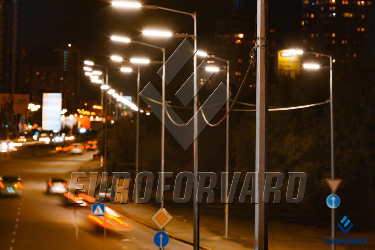 Опори вуличного освітлення на фоні автотрафіку в місті
