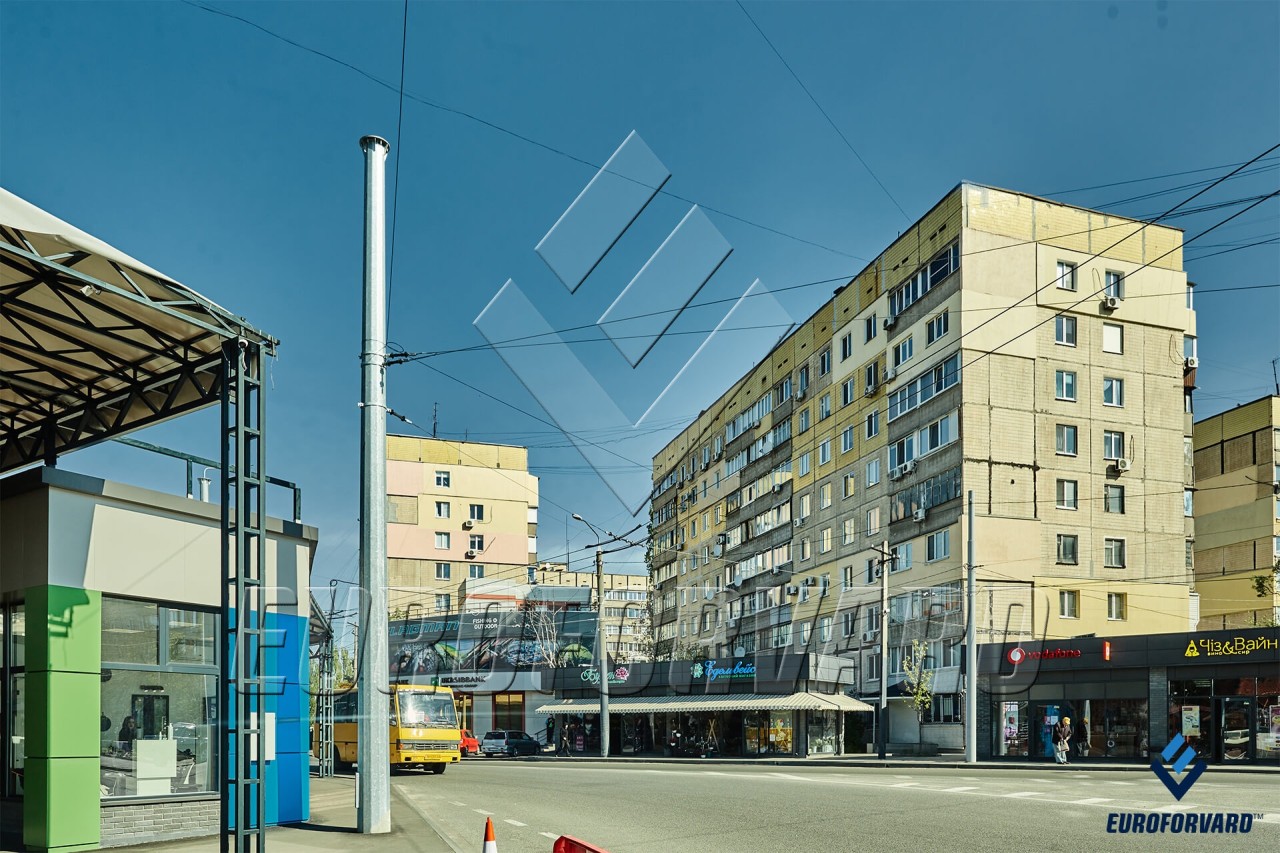 Опоры контактной сети металлические возле дороги и зданий в городе днем