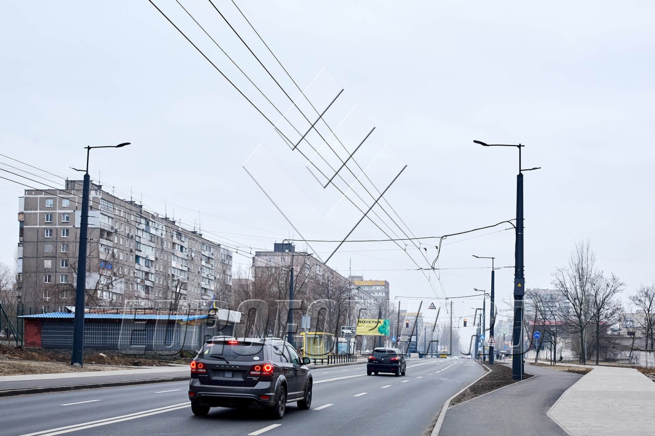 Опоры контактной сети с кронштейнами вдоль дороги в городе