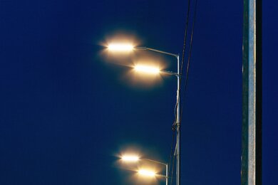 Опоры уличного освещения металлические, освещенные ночью