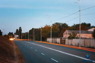 Опоры уличного освещения металлические вдоль асфальтированной дороги