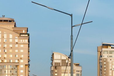 Опоры уличного освещения в городе на фоне высоких зданий