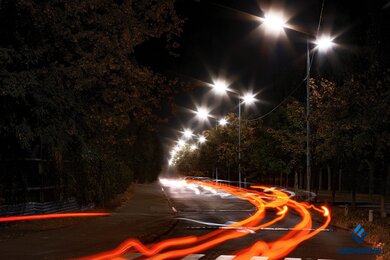 Опоры уличного освещения в городе на фоне быстрого движения транспорта