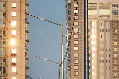 Опоры уличного освещения в городе на фоне многоэтажек