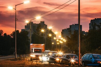 Опоры уличного освещения в городе возле дороги на фоне вечернего неба