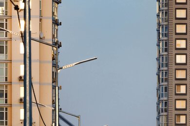 Опоры уличного освещения возле высоких зданий, вид слева