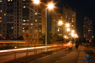 Опоры уличного освещения на улице города возле высоких зданий