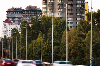 Опоры уличного освещения в городе на фоне зданий