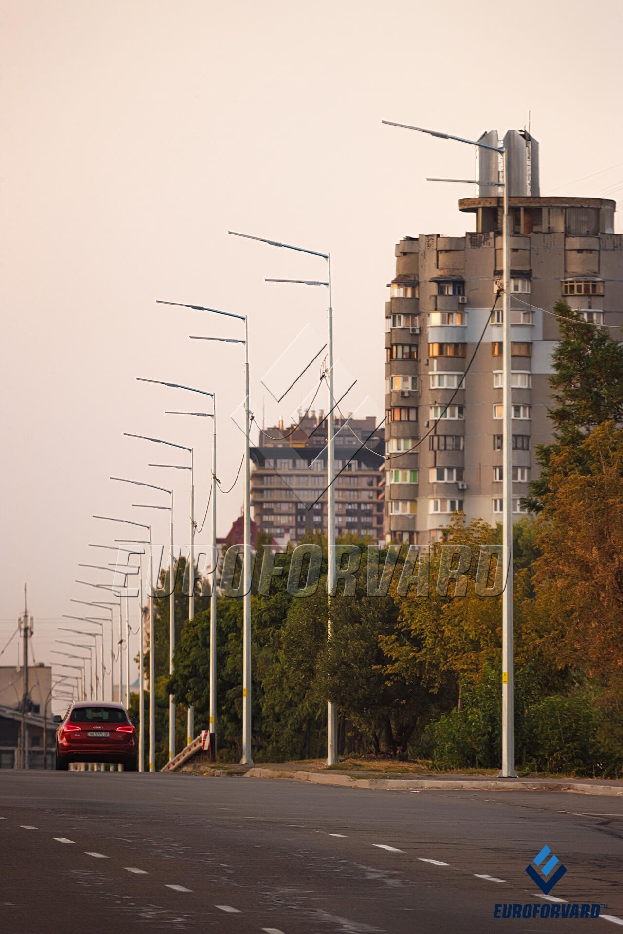 Опоры уличного освещения на фоне городских зданий