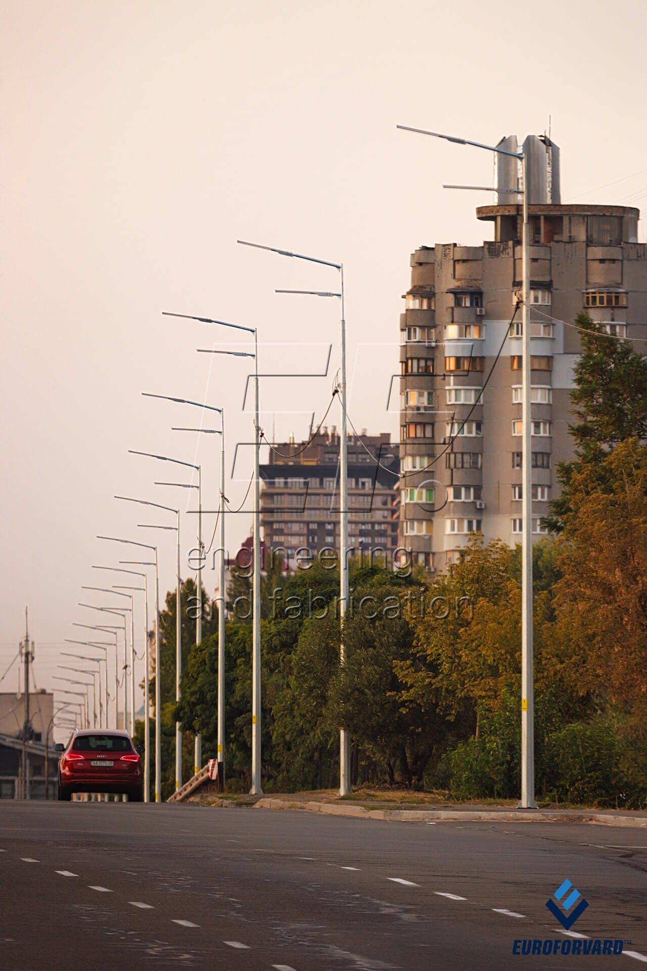 Опоры уличного освещения на фоне городских зданий