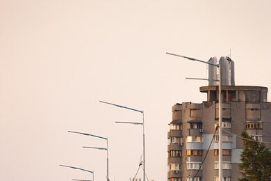 Опоры уличного освещения на фоне городских зданий