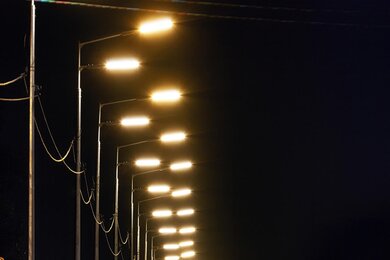 Опоры уличного освещения возле дороги в темноте, вид слева