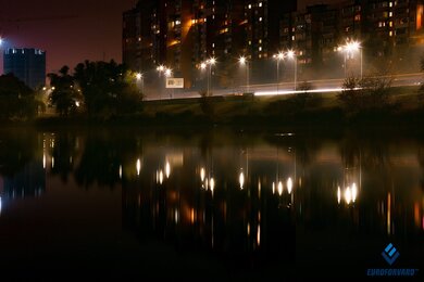 Опоры уличного освещения в городе, на фоне водоема в темноте
