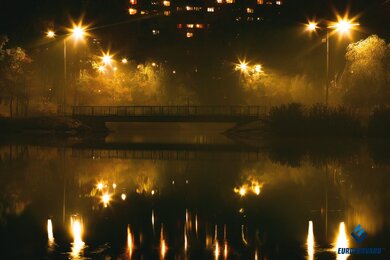 Опоры уличного освещения на фоне моста через водоем