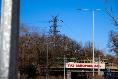 Опоры уличного освещения днем возле железнодорожного моста