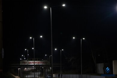 Опоры уличного освещения ночью возле железнодорожного моста