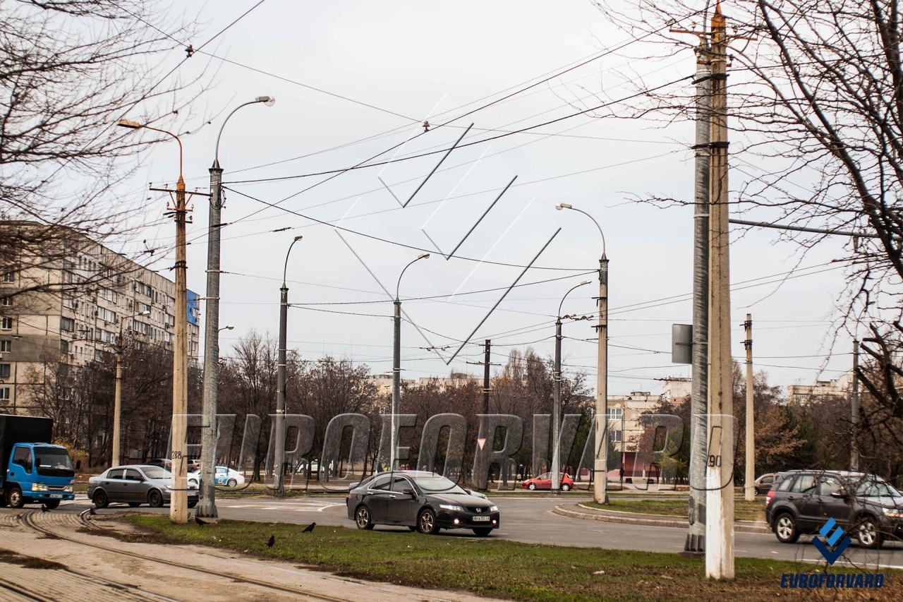 Опори контактної мережі міського електротранспорту з світильниками вздовж дороги