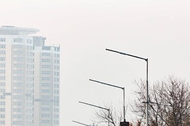 Опори вуличного освітлення в місті, на фоні будинків та дороги