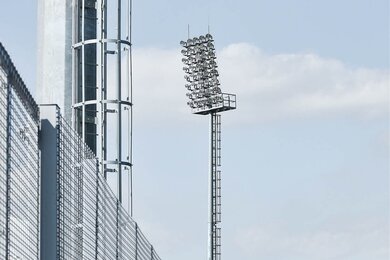 Стадионные мачты освещения рядом с ограждением спортивного стадиона
