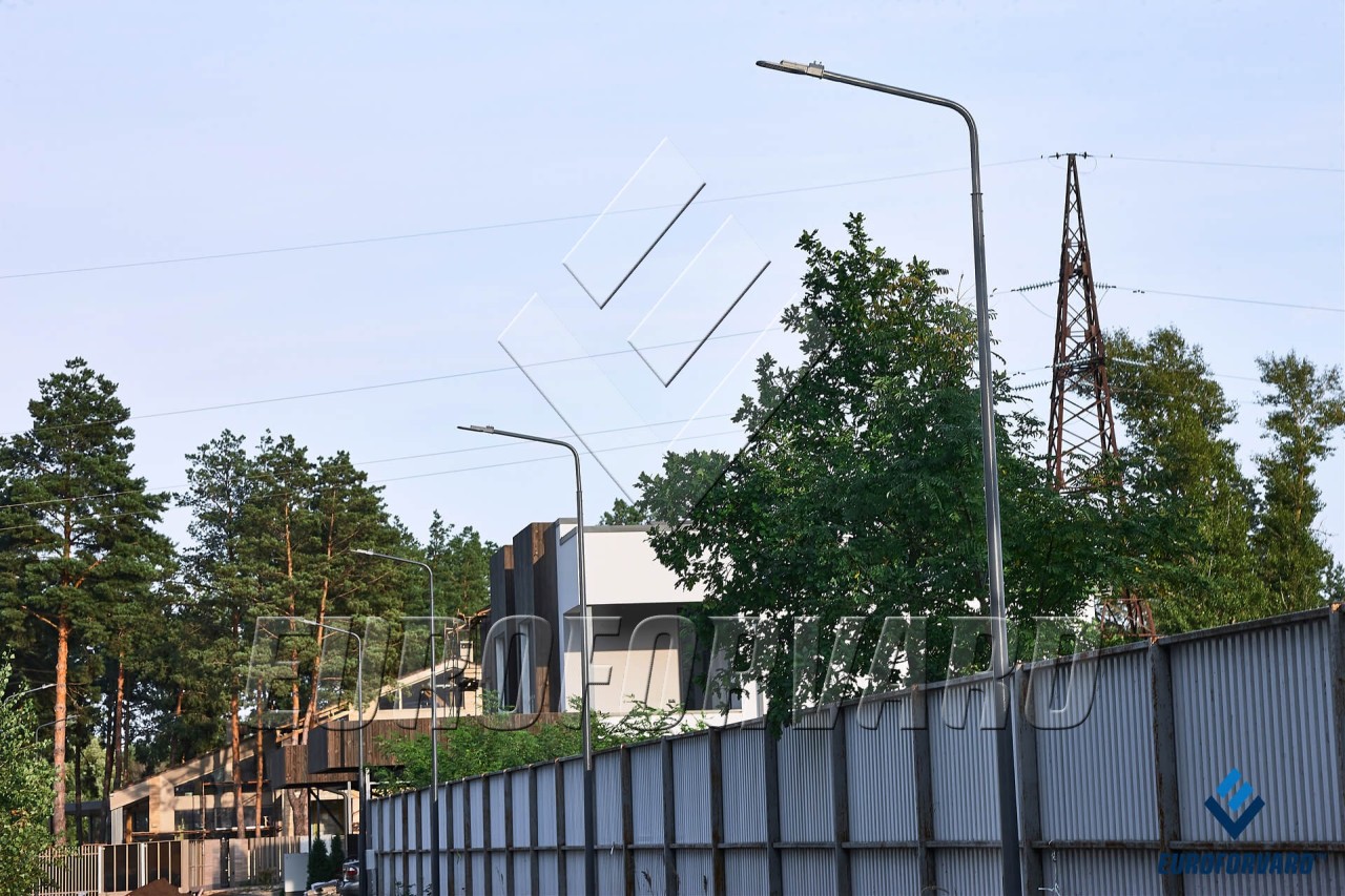 Опори паркового освітлення біля огорожі 