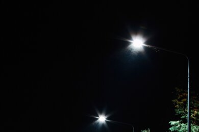 Опоры паркового освещения возле ограждения в темноте