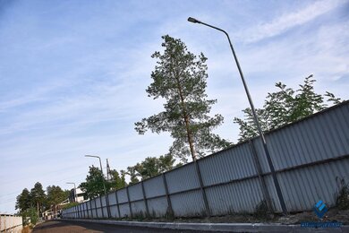 Опоры паркового освещения возле забора в комплексе днем