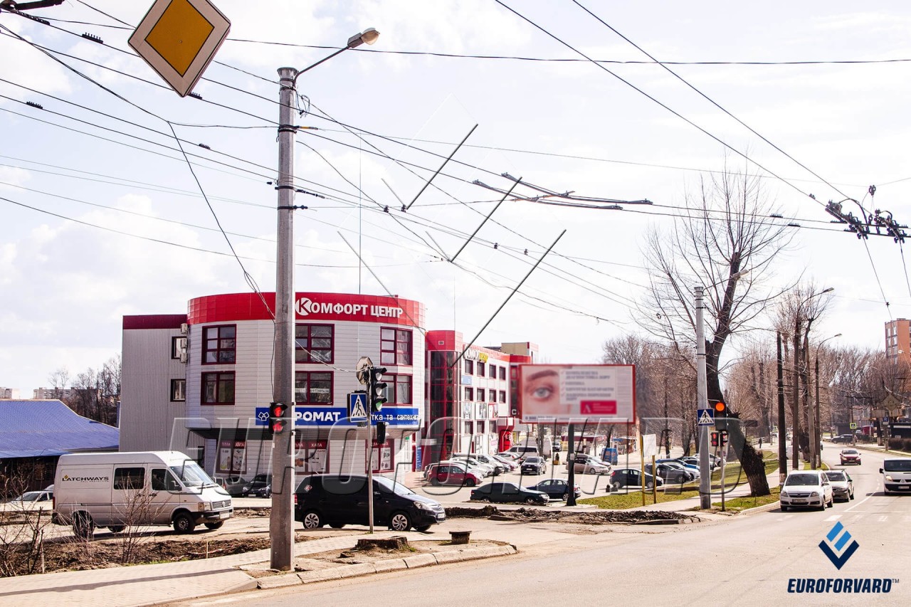 Опори контактної мережі біля дороги на фоні будівлі