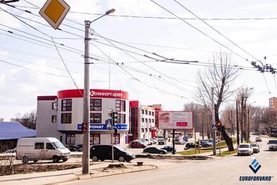 Опори контактної мережі біля дороги на фоні будівлі