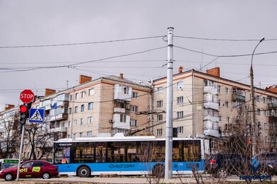 Опоры контактной сети возле дороги на фоне городских зданий