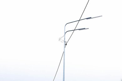 Опоры уличного освещения возле автодороги днём