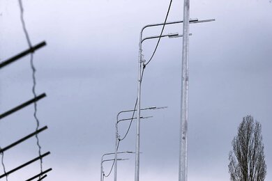 Опоры уличного освещения с двухрядными кронштейнами вдоль дороги днём