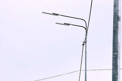 Опоры уличного освещения с двухрядными кронштейнами на фоне неба