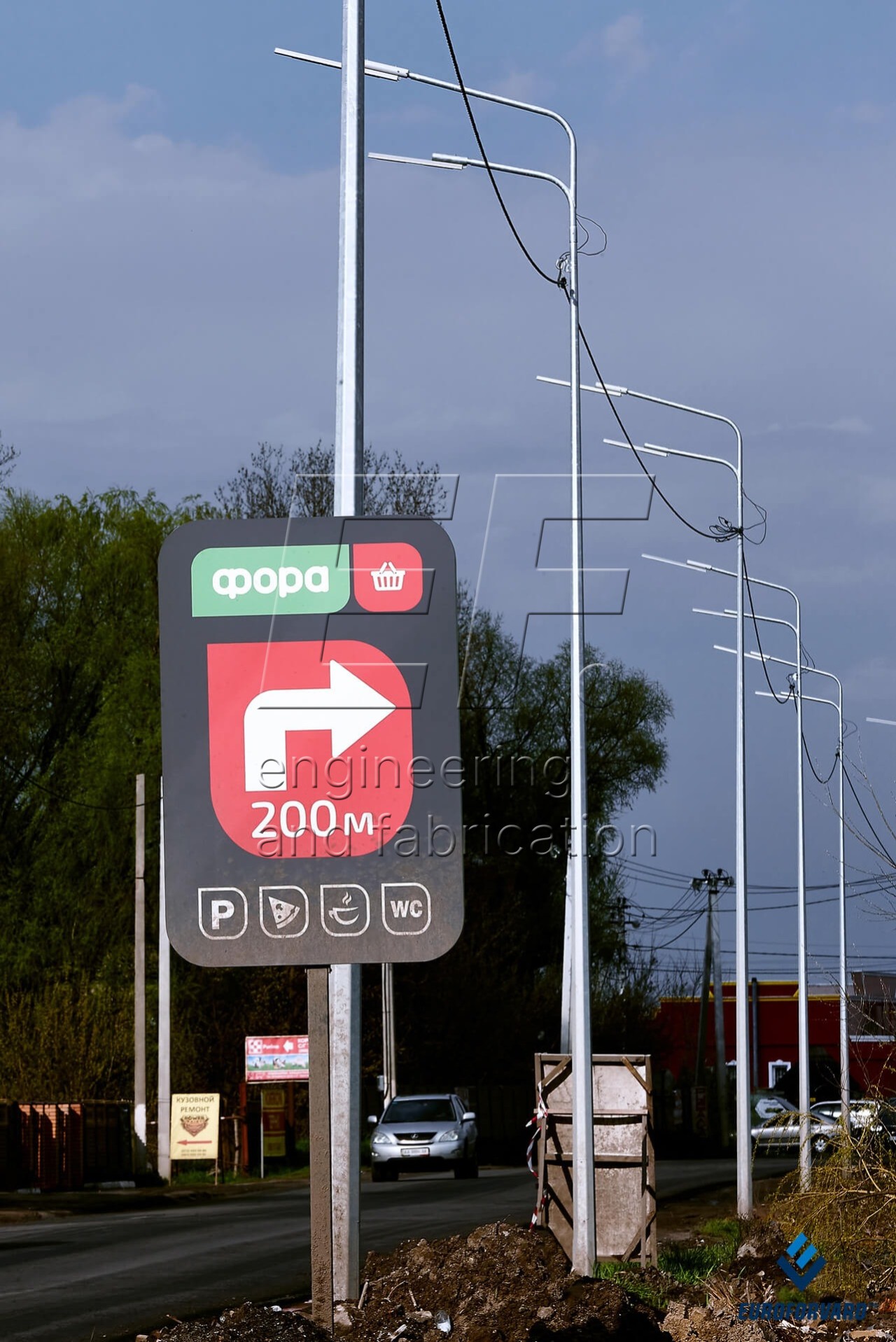 Опоры уличного освещения с двухрядными кронштейнами возле автомобильной дороги