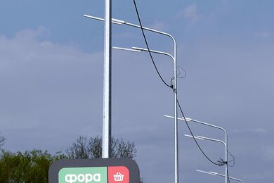 Опоры уличного освещения с двухрядными кронштейнами возле автомобильной дороги
