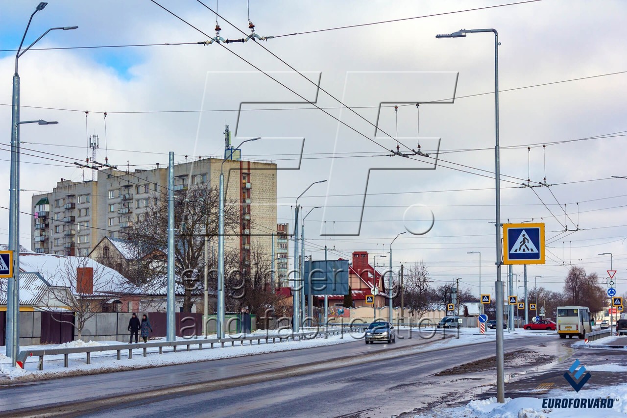 Опоры контактной сети фланцевые возле городской дороги днем