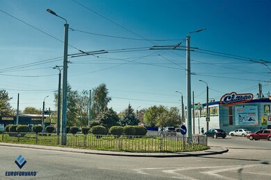 Опори контактної мережі металеві біля міської дороги вдень