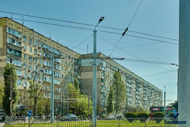 Опори контактної мережі металеві біля дороги на фоні будівель