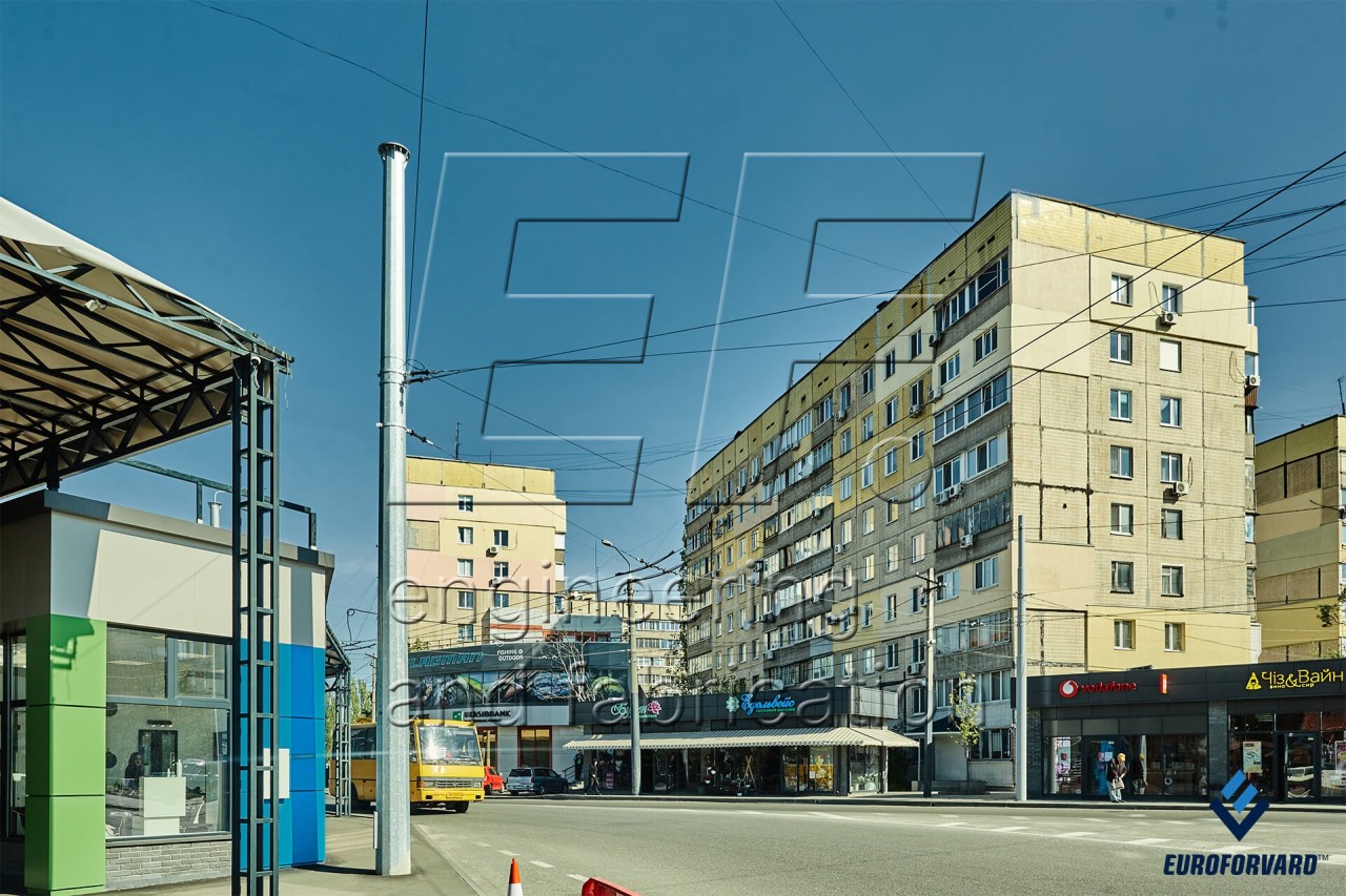 Опоры контактной сети металлические возле дороги и зданий в городе днем