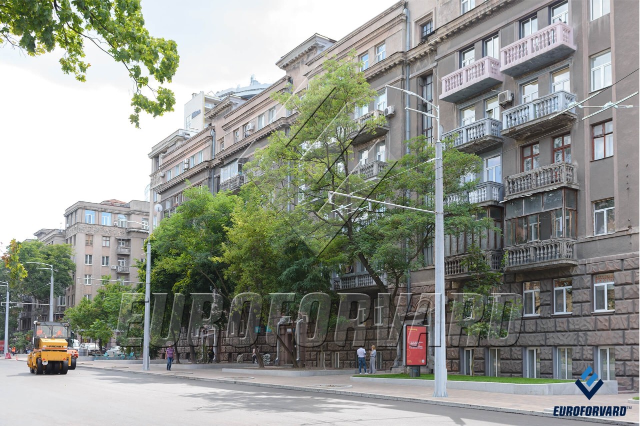 Опори контактної мережі біля дороги та будівель в місті