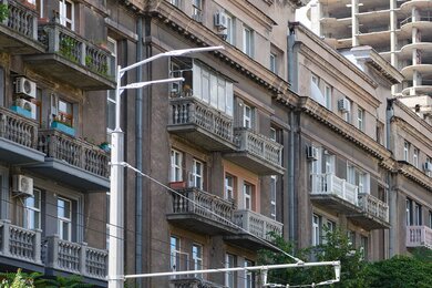Опори контактної мережі поруч з дорогою та будівлями в місті