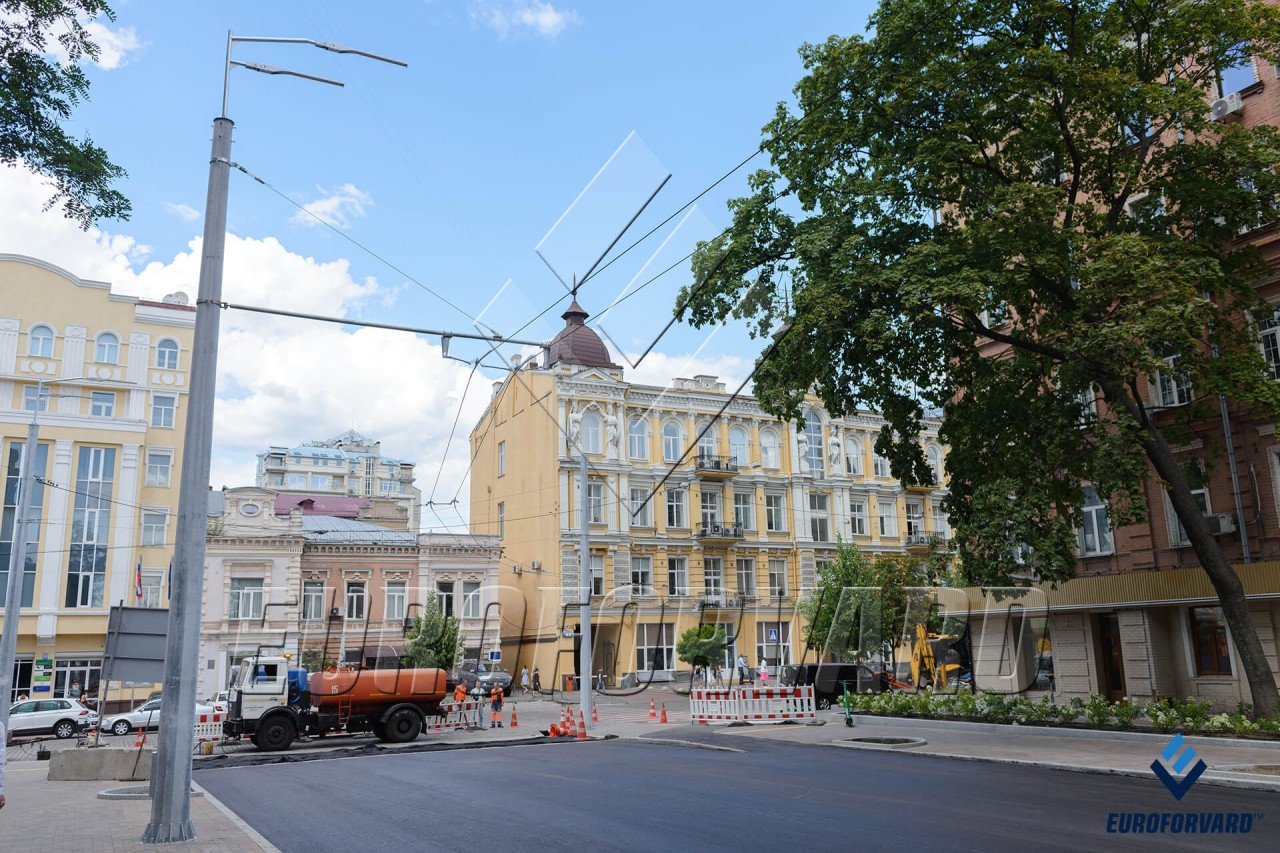 Опори контактної мережі поруч з дорогою та міськими будівлями