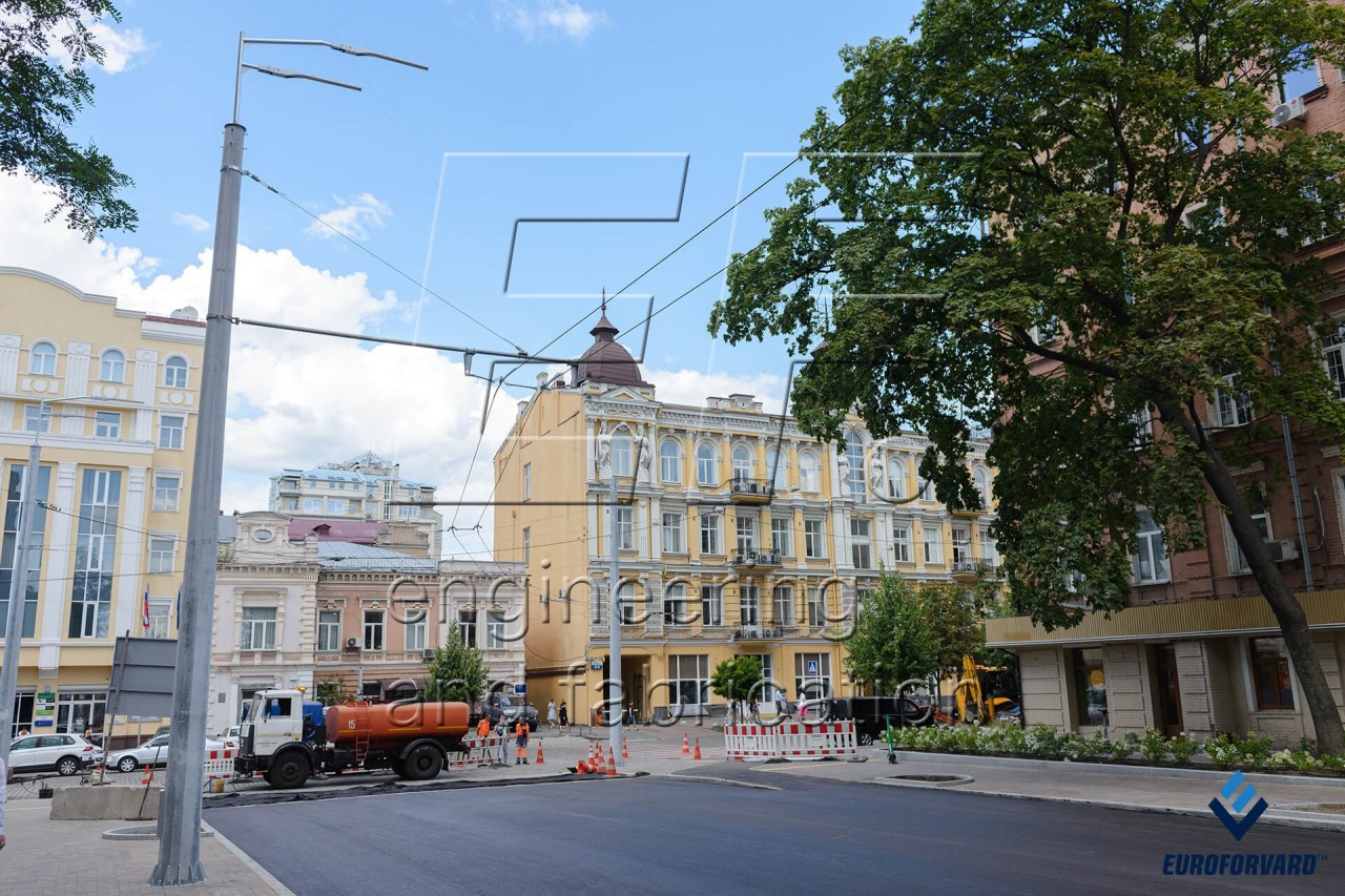Опори контактної мережі поруч з дорогою та міськими будівлями