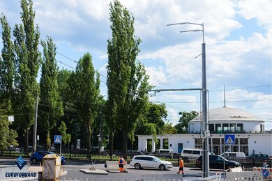 Опоры контактной сети возле дороги на фоне здания метро