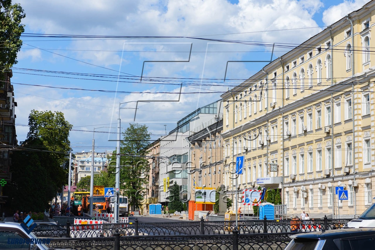 Опоры контактной сети на тротуаре возле городской дороги и зданий