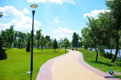 Опори паркового освітлення на фоні зелених насаджень