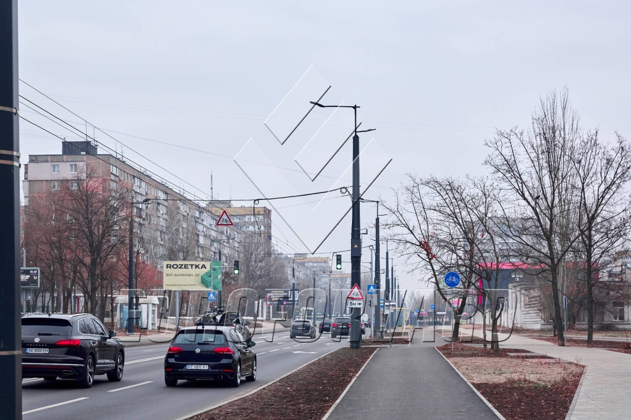 Опори контактної мережі з кронштейнами біля міської дороги