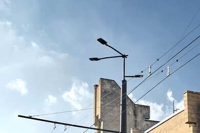 Опори контактної мережі багатогранні біля міської дороги та будівель