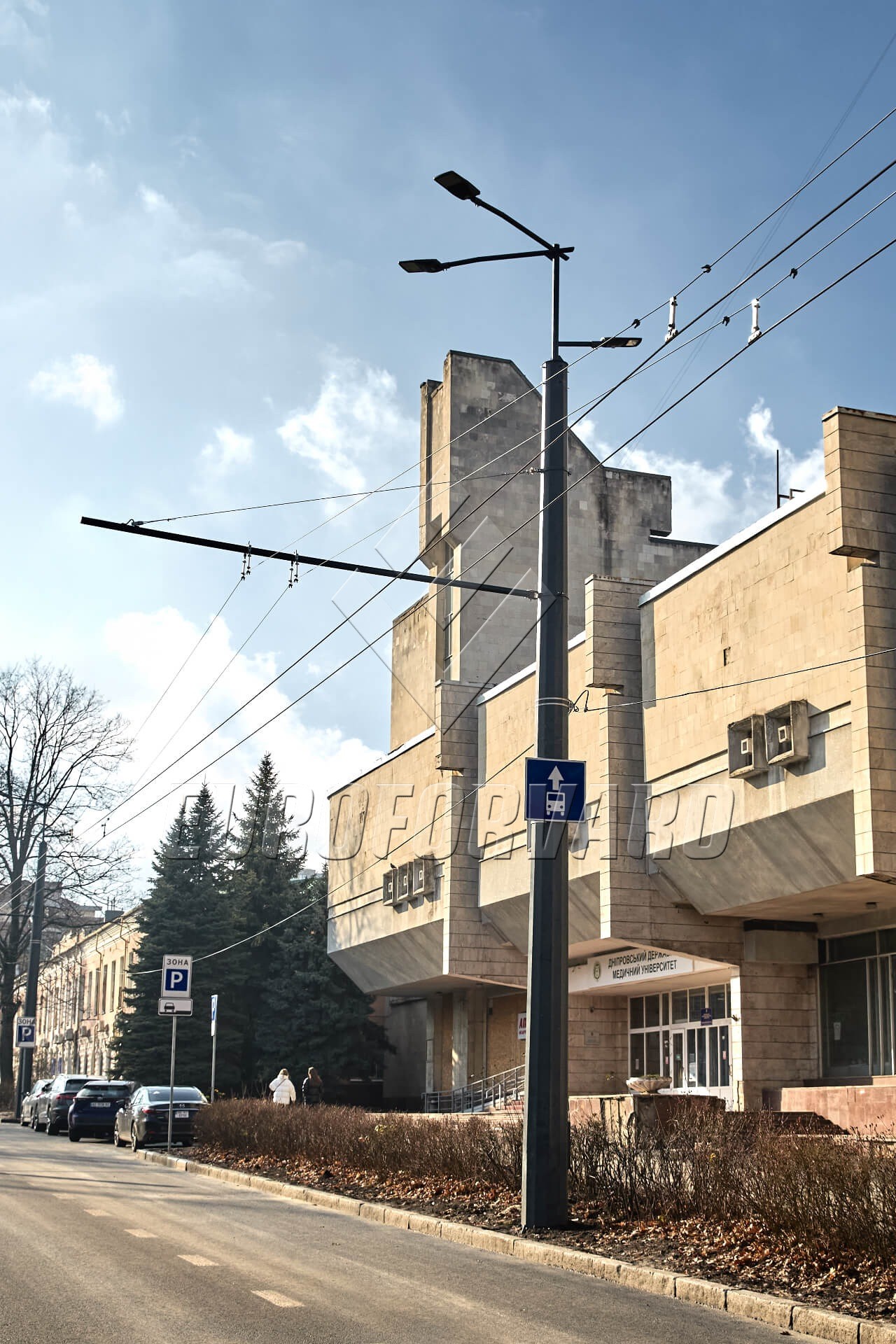 Опоры контактной сети многогранные рядом с городской дорогой и зданиями